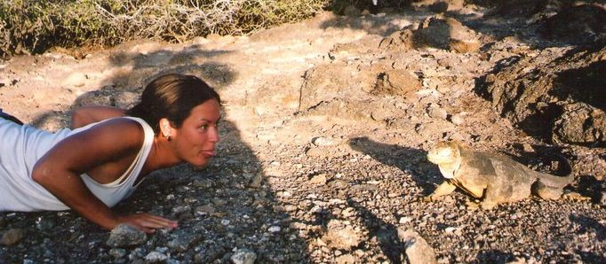 Tour Guide and Naturalist Victoria Africano interacting with an Iguana in the Galapagos Islands, Ecuador